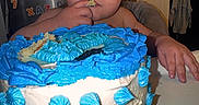 Xavier is registered to the contest to win money with this photo: child, toddler, baby, birthday, cake, frosting, blue_frosting, eating, smiling, face, portrait, indoor, kitchen, refrigerator, alphabet_magnets, table, dessert, celebration, home, photograph