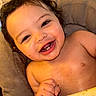baby, bare_chest, chair, child, closeup, curly_hair, cushion, eyes, face, food, happy, indoor, infant, laughing, plate, portrait, sitting, smiling, teeth, warm_lighting