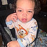 Xavier is registered to the contest to win money with this photo: baby, child, infant, curly_hair, portrait, sitting, stroller, pajamas, clothing, cartoon, colorful, blanket, stuffed_toy, indoors, face, eyes, mouth, hand, cozy, photography