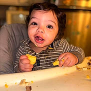 Xavier joined the competition — help win amazing prizes! baby, child, toddler, high_chair, sitting, face, portrait, smiling, happy, food, eating, hands, eyes, hair, striped_clothing, indoor, kitchen, dining, tray, crumbs