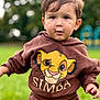 Simba, cartoon_character, casual, child, clothing, cute, daylight, expression, face, fun, grass, greenery, hoodie, nature, outdoor, person, playground, portrait, toddler, young_child
