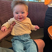 Iris joined the competition — help win amazing prizes! baby, child, smiling, happy, person, striped_shirt, blue_jeans, hair, face, hand, sitting, indoor, window, bench, adult_hand, casual_clothing, cute, portrait, skin, young