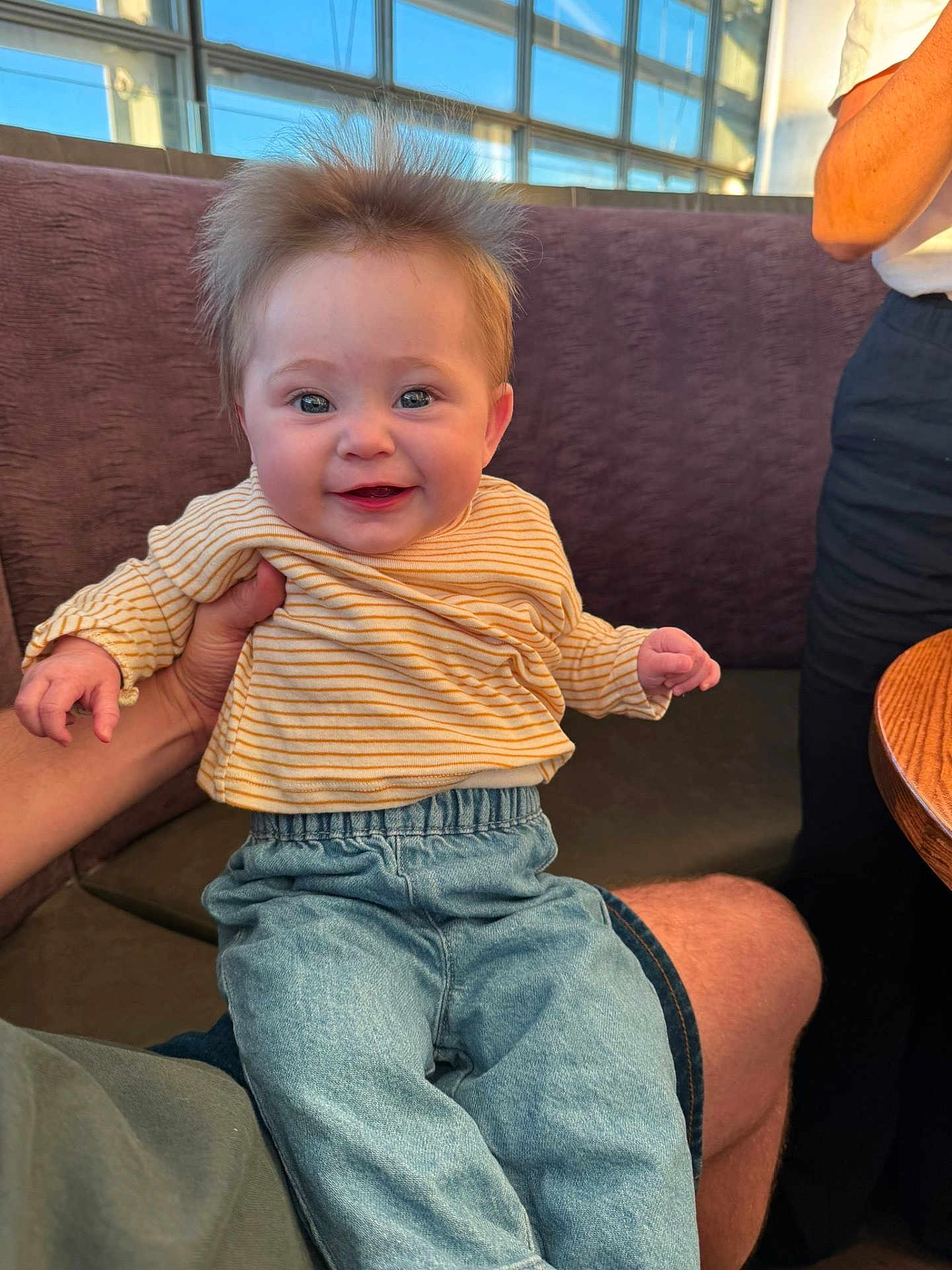 Iris joined the competition — help win amazing prizes! baby, child, smiling, happy, person, striped_shirt, blue_jeans, hair, face, hand, sitting, indoor, window, bench, adult_hand, casual_clothing, cute, portrait, skin, young