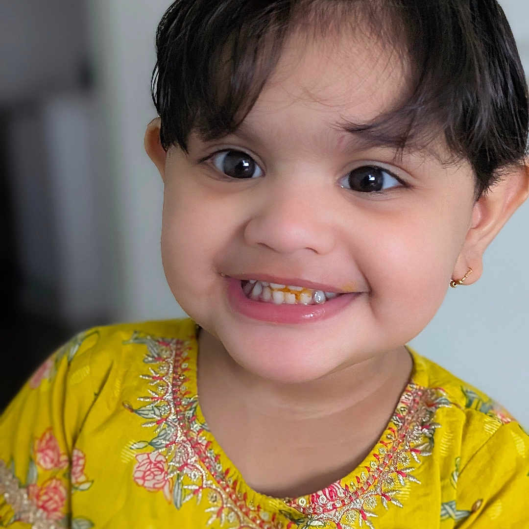 Nikki is registered to the contest to win money with this photo: big_eyes, black_hair, child, childhood, closeup, cute, earrings, face, fashion, floral_pattern, flower_clip, happy, indoors, joy, person, portrait, smiling, toddler, yellow_dress, young_child