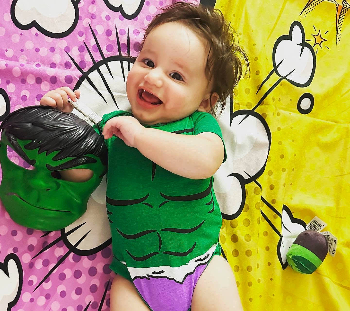 Edward is registered to the contest to win money with this photo: arm, baby_toddler_clothing, cheek, eye, face, facial_expression, finger, gesture, green, hand, happy, head, joy, organ, people_in_nature, person, pink, skin, smile, textile