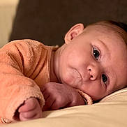 Aria a rejoint le concours — aidez-le/la à gagner de superbes lots ! baby, infant, child, face, eyes, cheek, hand, arm, onesie, fabric, soft_texture, portrait, close_up, lying_down, couch, sofa, indoor, newborn, gaze, cute