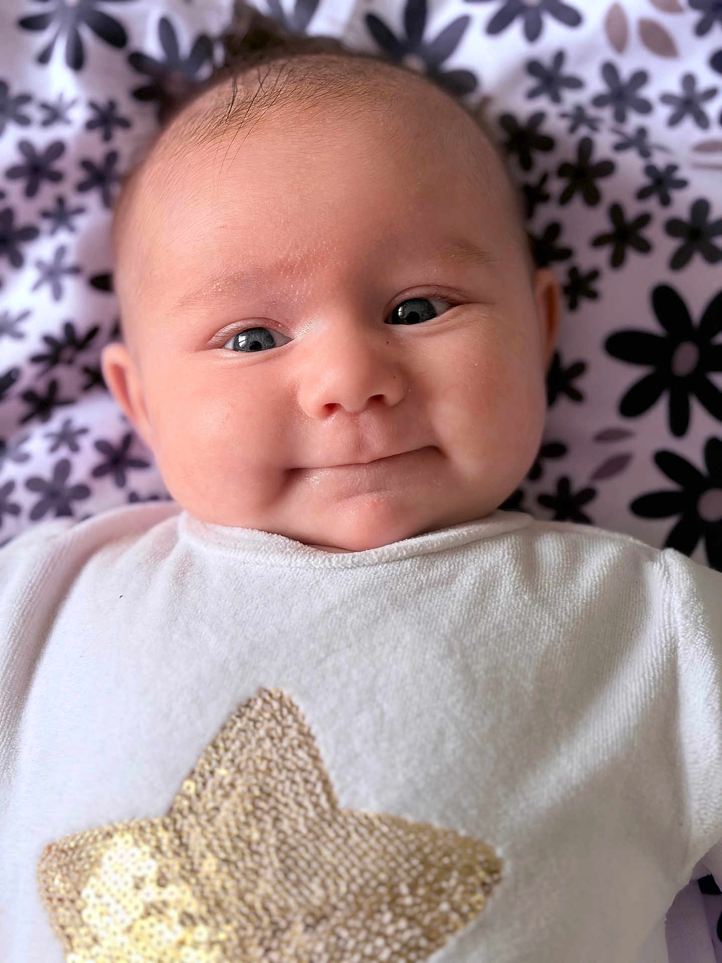 Aria a rejoint le concours — aidez-le/la à gagner de superbes lots ! baby, infant, child, face, smile, cheeks, eyes, onesie, star_sequin, blanket, floral_pattern, portrait, close_up, lying_down, cute, soft_texture, skin, gaze, head, expression