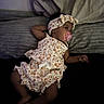 baby, infant, pacifier, headband, floral_outfit, bed, pillow, sleepwear, child, lying_down, cute, indoors, peaceful, resting, soft_lighting, portrait, young_child, fabric, texture, relaxing