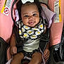 Kailyn is registered to the contest to win money with this photo: baby, smiling, car_seat, bow, curly_hair, bib, daisy_pattern, white_socks, infant, cute, happy, child, seatbelt, pink, black_clothing, person, indoor, portrait, toddler, playful