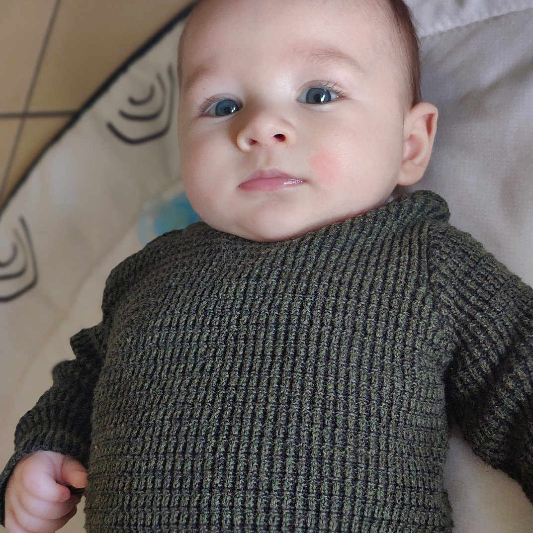 Kenneth a rejoint le concours — aidez-le/la à gagner de superbes lots ! baby, child, closeup, cute, expression, eyes, face, hand, head, indoor, infant, knitwear, lying_down, patterned_background, person, portrait, skin, soft_surface, sweater, young_child