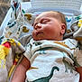 baby, newborn, sleeping, infant, dinosaur_print, onesie, blanket, duck_pattern, hospital_bassinet, medical, child, cute, soft_light, peaceful, portrait, closeup, skin, face, arm, indoors