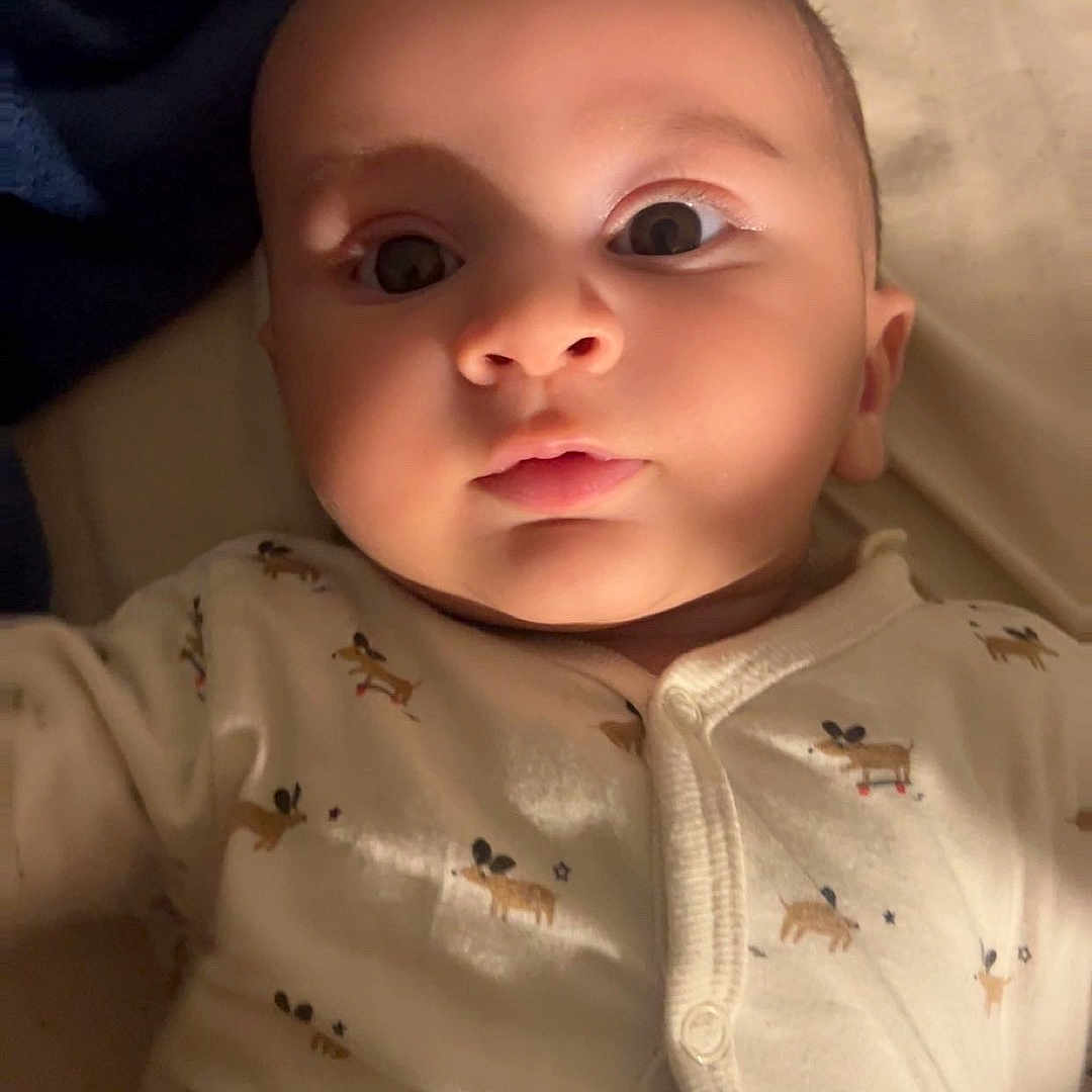 Yassir a rejoint le concours — aidez-le/la à gagner de superbes lots ! animal_print, baby, bed, blanket, child, closeup, cute, expression, eyes, face, head, indoors, infant, onesie, person, portrait, skin, sleepwear, soft_lighting, young