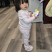 Abigail joined the competition — help win amazing prizes! toddler, child, toy, indoor, flooring, wood_floor, standing, clothing, long_hair, expression, room, household, furniture, cabinet, plastic_bottle, chair, table, slipper, pajamas, curious