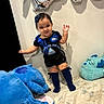 Abigail is registered to the contest to win money with this photo: toddler, child, plush_toy, bed, balloon, blue, smile, socks, shorts, shirt, hair_bow, indoor, happy, person, cute, toy, face, celebration, wall, floor