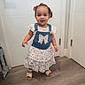 Abigail is registered to the contest to win money with this photo: toddler, child, girl, standing, indoor, dress, denim, bow, hair_bow, sandals, flooring, door, smile, curly_hair, white_wall, floor, clothing, person, happy, cute