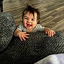 baby, child, smiling, happy, face, hands, blanket, gray, hair, indoor, floor, wooden_floor, candid, cute, infant, person, home, cozy, expression, joyful