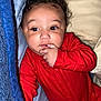 baby, infant, red_onesie, bed, blanket, curly_hair, hand, face, eyes, skin, cute, child, sleepwear, indoors, portrait, person, resting, cozy, comfort, young