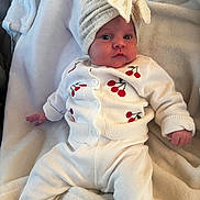 Lou participe au concours pour gagner de l'argent avec cette photo : baby, infant, newborn, hat, bow, blanket, white_clothing, cherry_pattern, cardigan, onesie, cute, portrait, indoors, soft_fabric, cozy, lying_down, eyes, hand, sleeve, plush