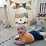 Ruben is registered to the contest to win money with this photo: baby, child, smiling, lying_down, playroom, tent, pillow, stuffed_animal, giraffe, toy, floor_mat, orange_shirt, navy_shorts, indoor, carpet, storage_box, colorful, cute, happy, infant