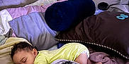 Leo is registered to the contest to win money with this photo: baby, sleeping, bed, blanket, pillow, pacifier, onesie, headboard, lamp, indoors, cozy, rest, child, curly_hair, soft_lighting, toddler, furniture, comfort, nap, home