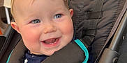 Gentry joined the competition — help win amazing prizes! baby, child, smile, face, headband, bow, stroller, seatbelt, blue_eyes, red_cheeks, clothing, patterned_clothes, happy, infant, person, indoor, black_stroller, teal_trim, cute, portrait