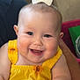 baby, child, smiling, yellow_dress, sunflower_pattern, bow, happy, cute, infant, portrait, indoors, sitting, holding, person, skin, face, hand, cheerful, closeup, young