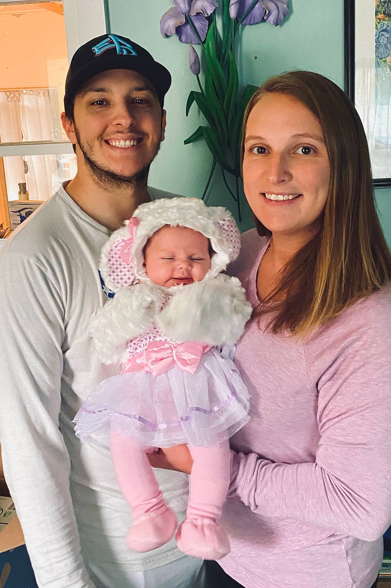 Viviana is registered to the contest to win money with this photo: baby, cap, child, comfort, eye, face, facial_expression, gesture, happy, headgear, headwear, interaction, joy, organ, person, picture_frame, pink, purple, shoulder, skin