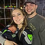 Beckett is registered to the contest to win money with this photo: baby, newborn, woman, man, couple, smile, sleeping, jersey, seahawks, baseball_cap, beard, window, reflection, bar_interior, necklace, hand, holding, portrait, nightlife, family