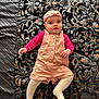érina participe au concours pour gagner de l'argent avec cette photo : baby, infant, child, headband, romper, tights, patterned_blanket, black, gold, pink, cute, lying_down, portrait, indoor, clothing, young_child, expression, face, person, soft_lighting