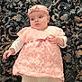 baby, infant, pink_dress, headband, knitted_clothing, white_tights, patterned_blanket, lying_down, cute, child, portrait, soft_lighting, indoors, adorable, young_child, fashion, baby_girl, textile, hand, face