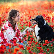 Shiny participe au concours pour gagner de l'argent avec cette photo : woman, dog, poppy_field, flowers, nature, outdoor, pet, friendship, smiling, kneeling, paw, black_dog, white_dog, grass, sunlight, happy, casual_clothing, spring, interaction, animal