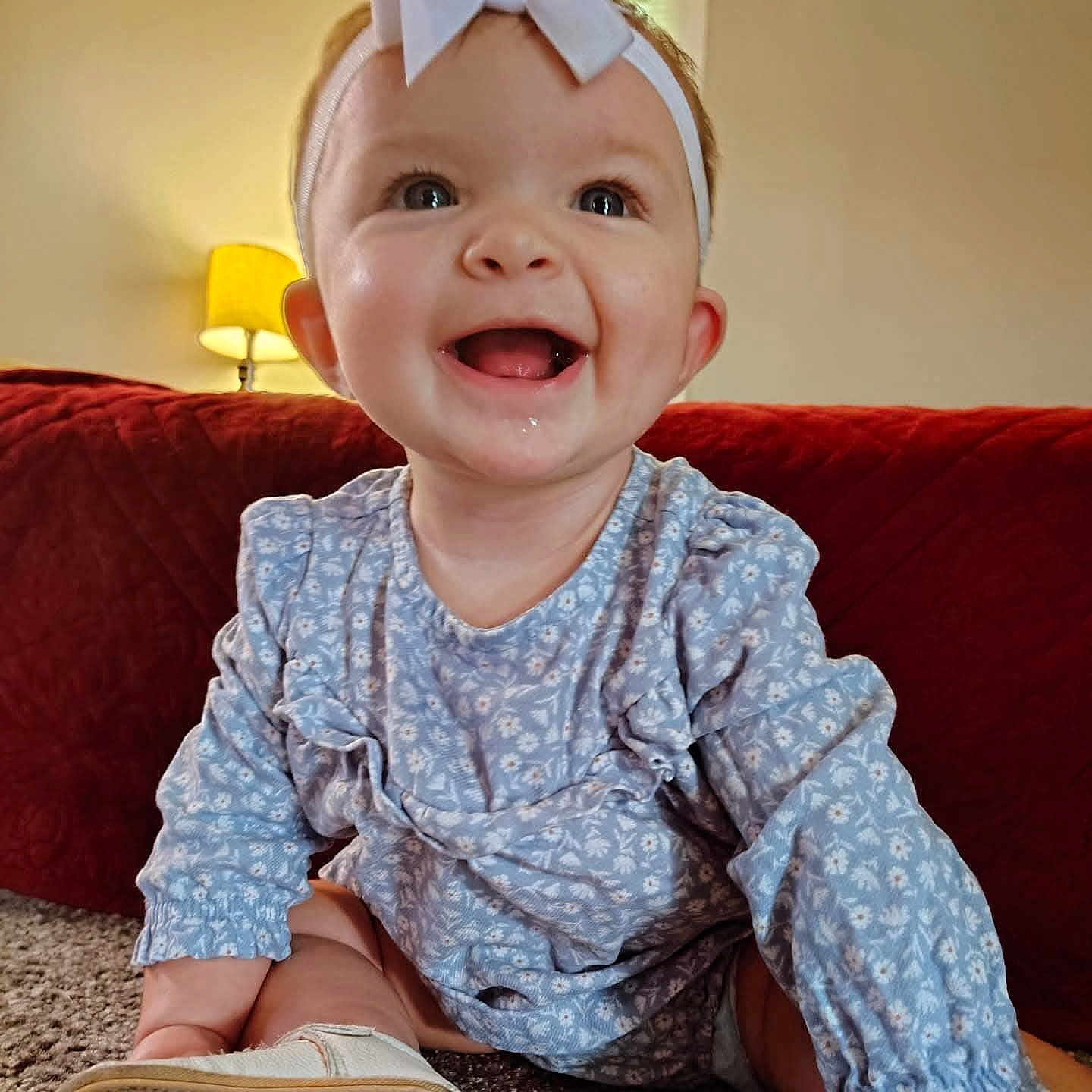 Brylee Grace is registered to the contest to win money with this photo: baby, blue_dress, bow, carpet, child, clothing, couch, cute, face, happy, headband, home, indoor, infant, lamp, person, portrait, sitting, smiling, toddler