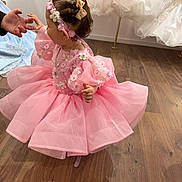 Mia.r participe au concours pour gagner de l'argent avec cette photo : child, toddler, pink_dress, party_dress, headband, bow, floral_applique, puff_sleeves, tutu, sparkle, necklace, hand, adult_hand, boutique, dress_shop, mannequin, wooden_floor, portrait, candid, happy