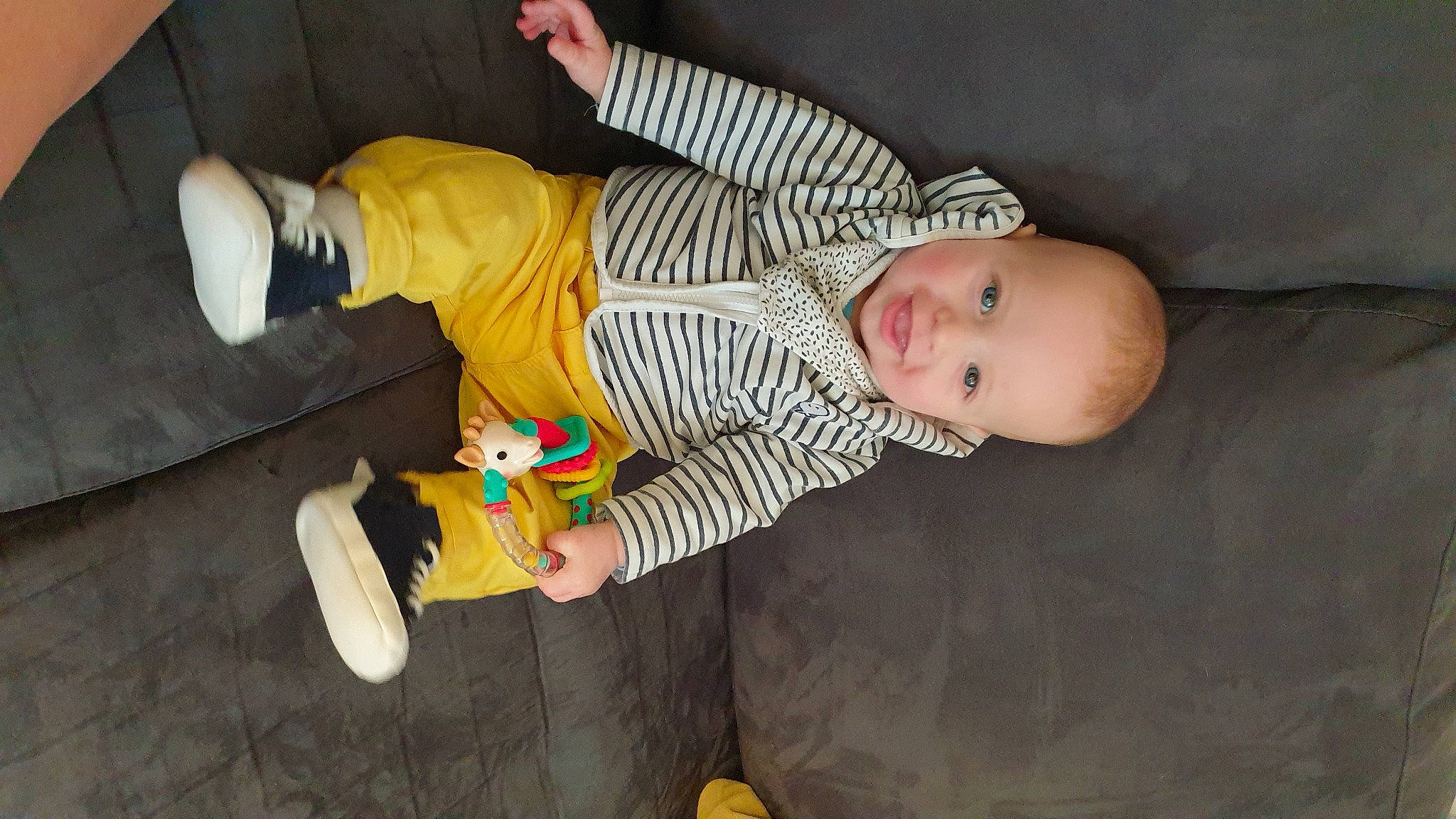 Maxime participe au concours pour gagner de l'argent avec cette photo : baby, baby_products, baby_toddler_clothing, child, comfort, flooring, fun, hardwood, leg, person, room, sitting, smile, toddler, wood, yellow