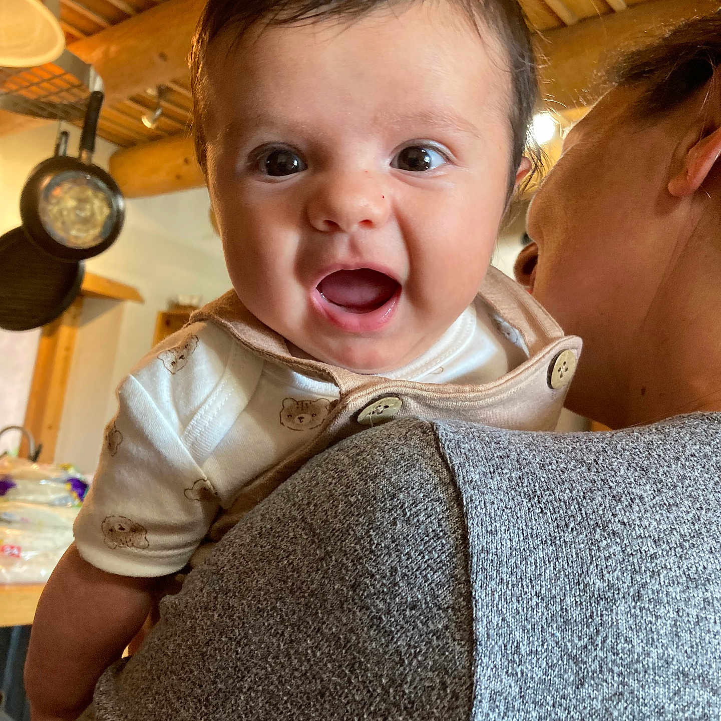 Ian is registered to the contest to win money with this photo: baby, button, candid, child, closeup, clothing, expression, face, happy, holding, indoor, kitchen, pan, person, portrait, smiling, sweater, warm_lighting, woman, wooden_ceiling