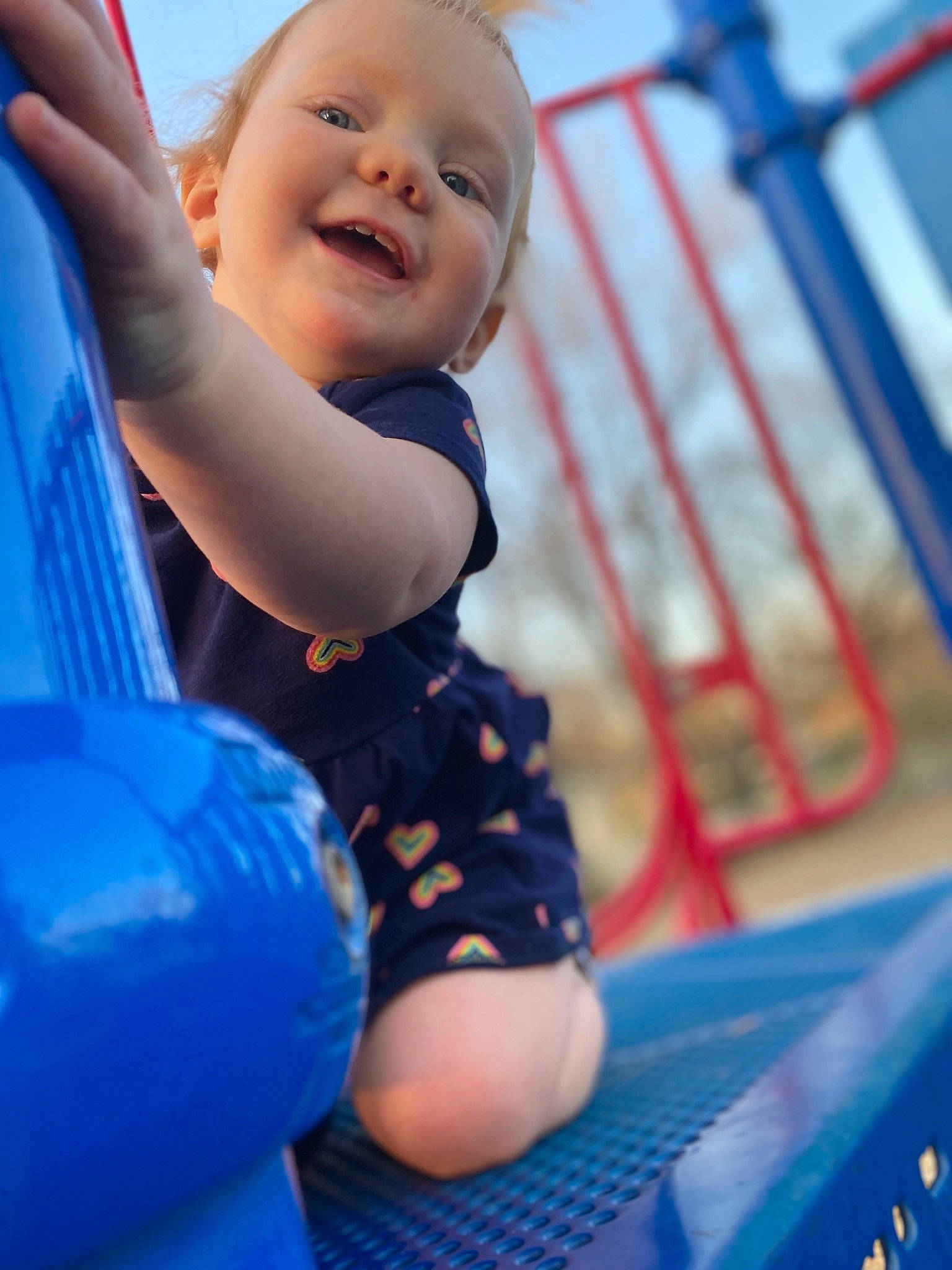 Lynleigh is registered to the contest to win money with this photo: baby, baby_toddler_clothing, blue, child, city, electric_blue, fun, happy, human_body, joy, leisure, outdoor_play_equipment, person, play, recreation, red, sitting, skin, sky, smile