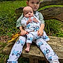 Archie is registered to the contest to win money with this photo: child, baby, siblings, bench, forest, grass, leaves, stick, nature, outdoor, clothing, shoes, face, holding, cute, greenery, wood, pants, sneakers, tongue