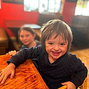 Nova is registered to the contest to win money with this photo: bodypart, boy, child, face, finger, furniture, hand, happy, hardwood, head, indoors, interiordesign, male, person, photography, plywood, portrait, restaurant, smile, wood