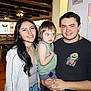 Nova is registered to the contest to win money with this photo: casual_clothing, ceiling_fan, certificate, chair, child, family, group, happy, holding, indoor, man, people, portrait, restaurant, smile, table, wall, woman, wooden_beams, young_adult