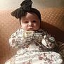 baby, child, infant, headband, bow, floral_pattern, couch, seated, clothing, portrait, face, indoors, soft_lighting, curious_expression, cute, young_child, texture, wrapped, sitting, cozy