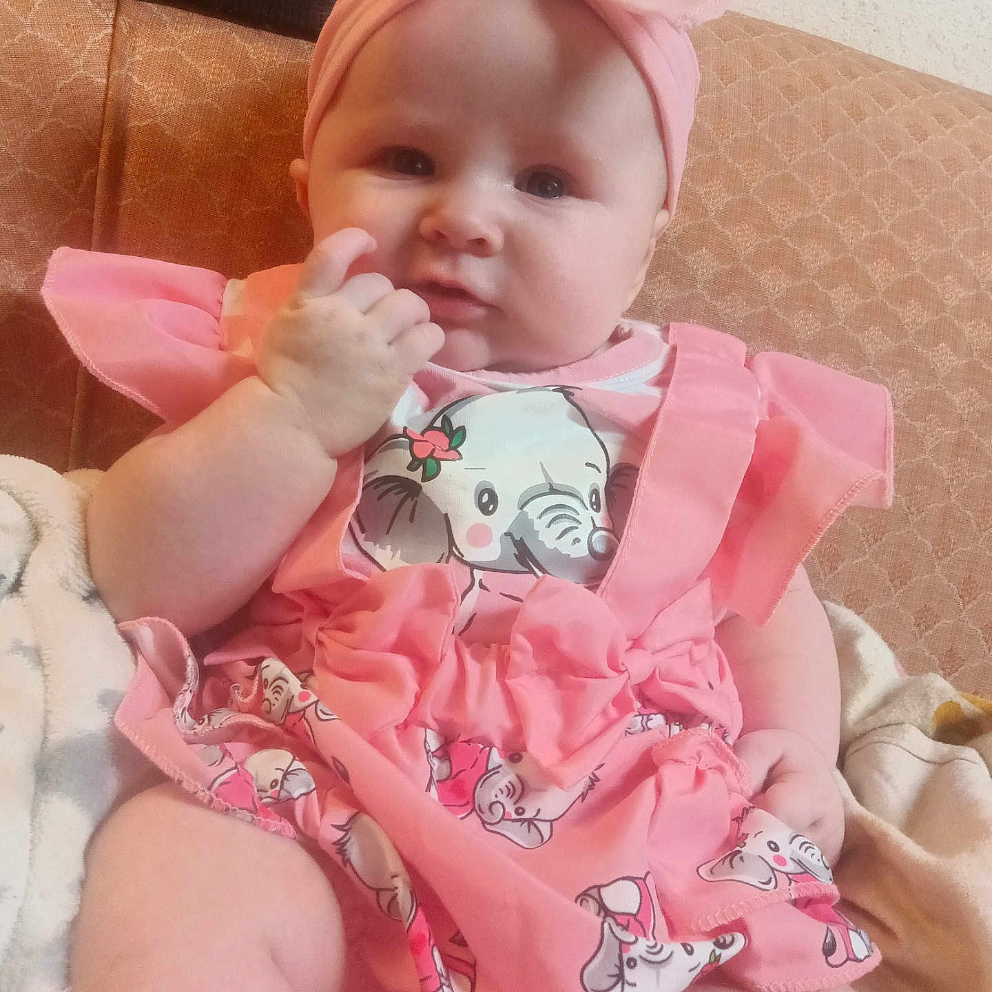 Ruby joined the competition — help win amazing prizes! adorable, baby, baby_dress, child, chubby_cheeks, comfort, couch, cute, elephant_print, hand_near_mouth, headband, headwear, indoor, infant, patterned_couch, pink_clothing, portrait, sitting, soft_fabric, young_child