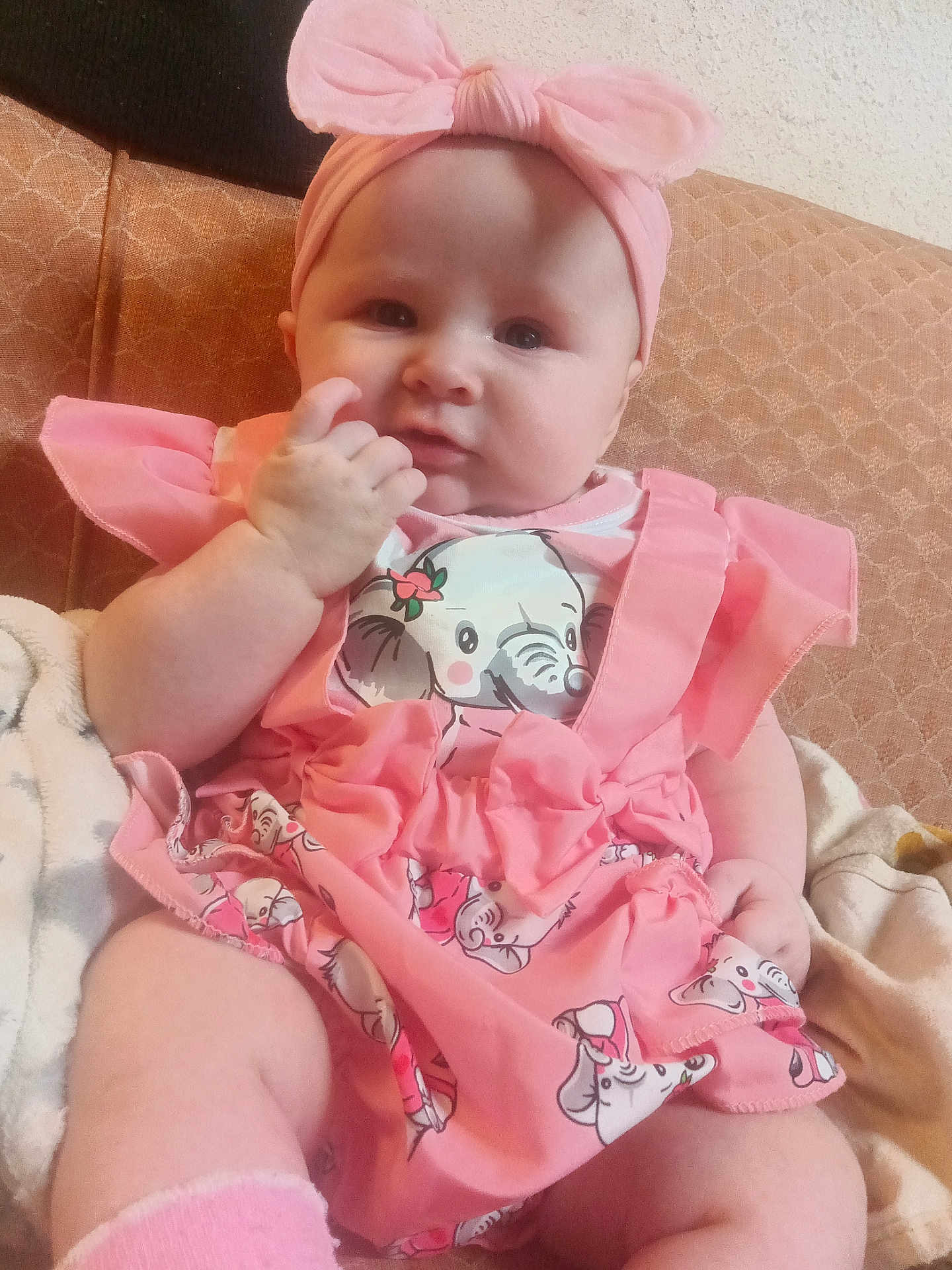 Ruby joined the competition — help win amazing prizes! baby, infant, pink_clothing, headband, elephant_print, couch, indoor, cute, chubby_cheeks, sitting, hand_near_mouth, soft_fabric, patterned_couch, child, portrait, adorable, baby_dress, headwear, comfort, young_child