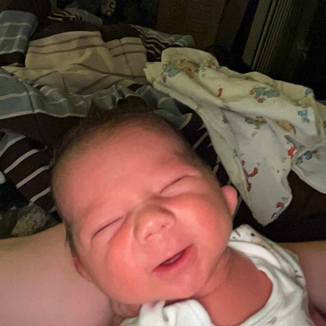 Stetson is registered to the contest to win money with this photo: newborn, baby, infant, sleeping, face, portrait, child, indoors, blanket, clothing, onesie, bed, cozy, close_up, scrunched_face, eyes_closed, small, home, dim_lighting, person