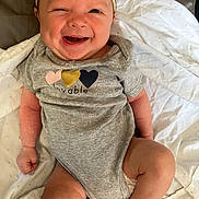 Kadence is registered to the contest to win money with this photo: baby, infant, smiling, winking, headband, onesie, gray_clothing, blanket, lying_down, cute, happy, child, skin, face, expression, indoors, newborn, small_hands, small_feet, cheerful