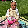 baby, child, grass, blanket, outdoor, sunlight, purse, pink, white_cardigan, floral_outfit, headband, barefoot, cute, serious_expression, sitting, person, foot, accessory, greenery, daylight
