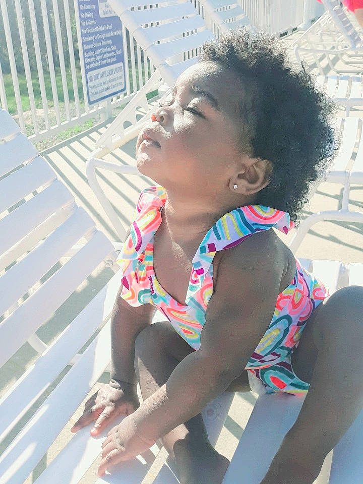 Megan is registered to the contest to win money with this photo: black_hair, child, electric_blue, fashion_accessory, fun, happy, human_leg, jewellery, leisure, pattern, person, recreation, sitting, skin, street_fashion, thigh, toddler, tourism, vacation