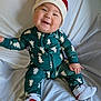 Henry joined the competition — help win amazing prizes! baby, child, smiling, sitting, santa_hat, christmas, holiday, onesie, green_clothing, white_background, happy, cute, infant, sock, patterned_clothing, portrait, indoors, festive, seasonal, face