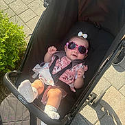 Freya joined the competition — help win amazing prizes! baby, sunglasses, stroller, outdoor, sunlight, pavement, shadows, pink, floral, clothing, grass, footwear, happy, child, person, sunny, seatbelt, cute, accessory, smile