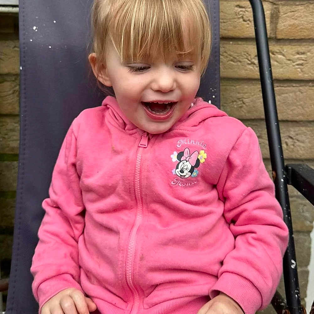 Lillie-J is registered to the contest to win money with this photo: bodypart, chair, child, clothing, coat, face, female, furniture, girl, happy, head, jacket, laughing, mouth, outdoors, pants, person, photography, portrait, sitting
