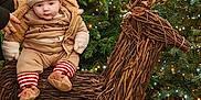 Elijah is registered to the contest to win money with this photo: baby, child, christmas, christmas_tree, cozy, cute, decorative_reindeer, festive, greenery, holiday, ivy, nature, outdoor, reindeer_hat, seasonal, smiling, twig_reindeer, twinkling_lights, warm_clothing, winter_clothing